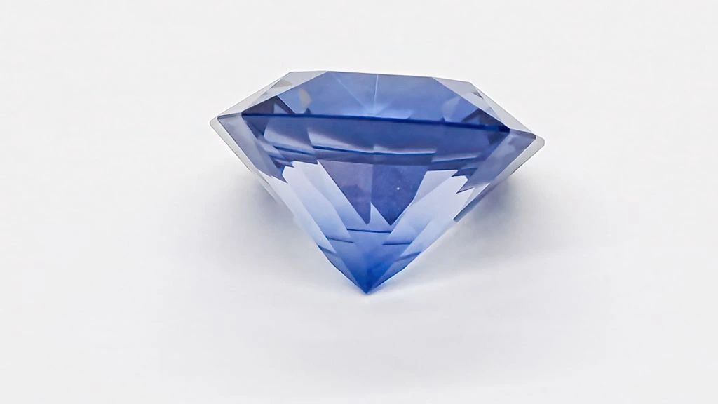 A faceted aquamarine gemstone resting on midnight velvet under studio light.