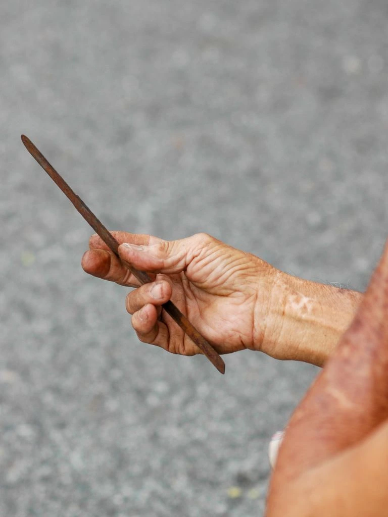 A master cutter's hands working a brass loupe over a rough aquamarine crystal