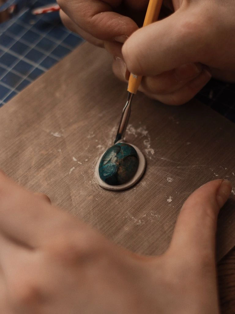 A cutter shaping a faceted aquamarine against a wet diamond lap